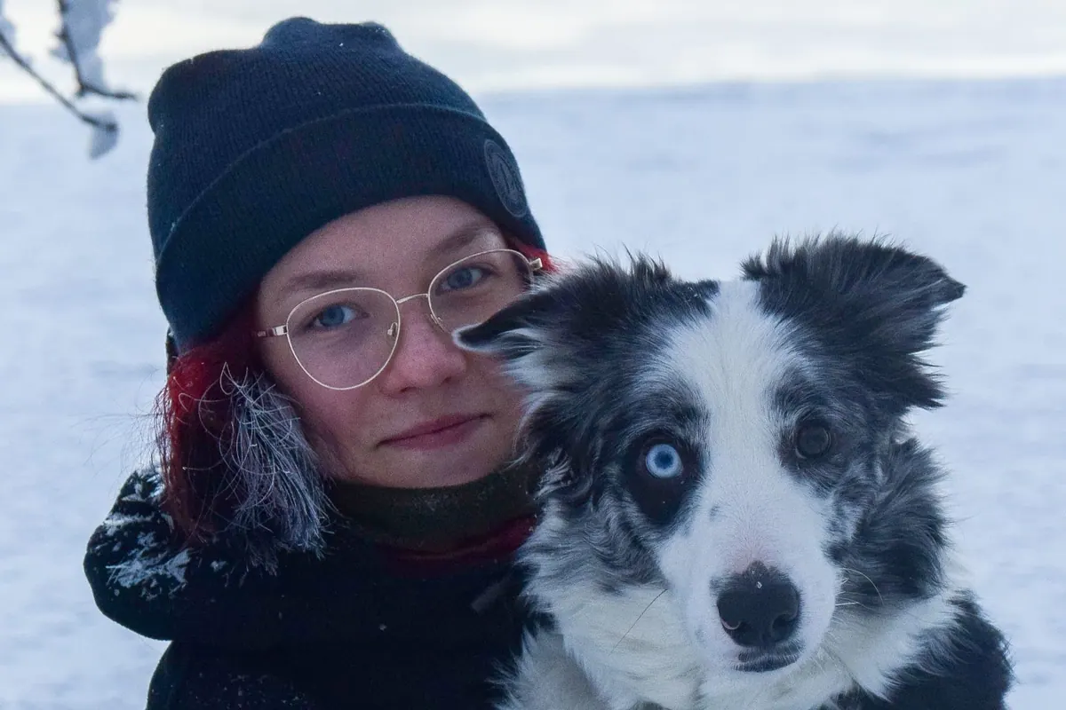 Kia istuu bordercollien pentujen kanssa portailla.